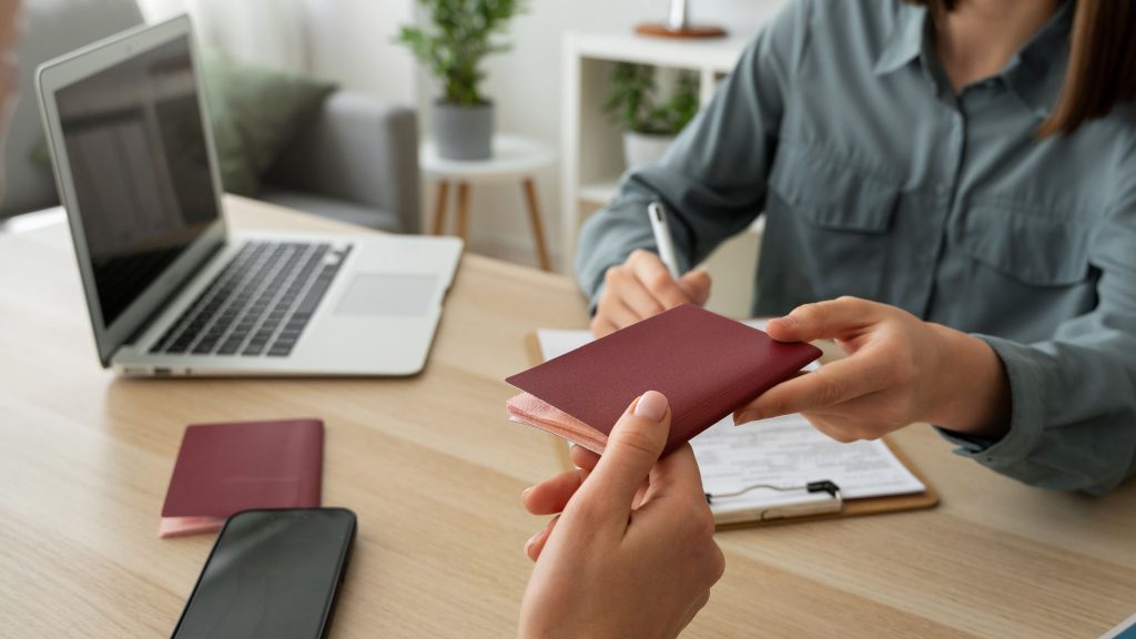 Persona entregando un pasaporte digital de producto en un entorno de trabajo, junto a un ordenador portátil y documentación.