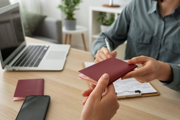 Persona entregando un pasaporte digital de producto en un entorno de trabajo, junto a un ordenador portátil y documentación.