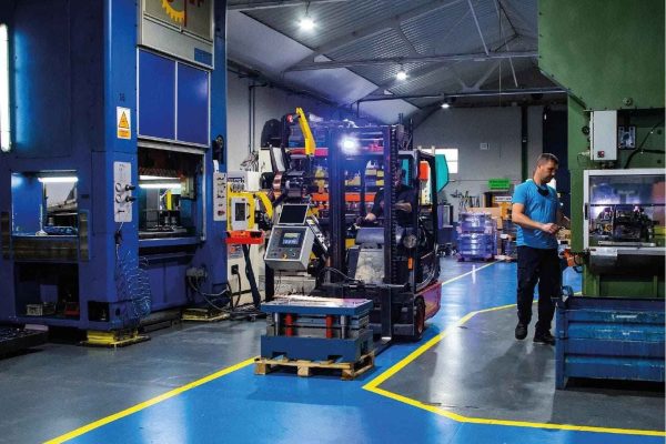 Operario trabajando en proceso de estampación de piezas metálicas en prensa industrial